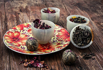 Image showing variety of dry tea leaves in jade stacks on wooden background