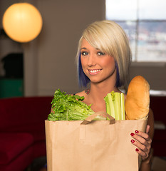 Image showing Attractive Female Homemaker Sets Grocery Bag on Counter