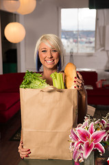 Image showing Attractive Female Homemaker Sets Grocery Bag on Counter