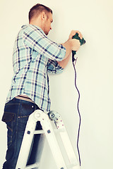 Image showing man with electric drill making hole in wall