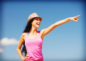 Image showing girl in hat showing direction on the beach