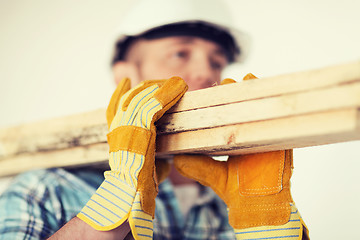 Image showing close up of male in gloves carrying wooden boards