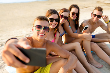 Image showing friends with smartphones on beach