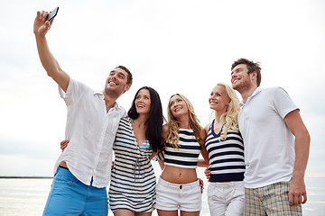 Image showing happy friends on beach and taking selfie