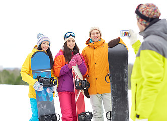 Image showing happy friends with snowboards and smartphone