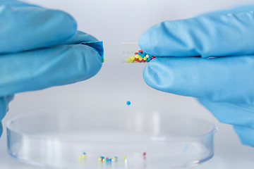 Image showing close up of scientist hands holding pill in lab