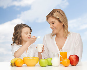 Image showing happy mother and daughter eating breakfast