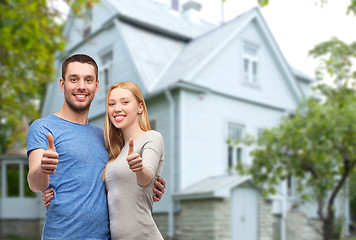 Image showing smiling couple showing thumbs up over house