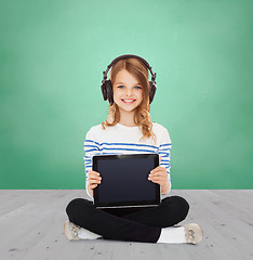 Image showing happy girl with headphones showing tablet pc