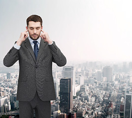 Image showing annoyed businessman covering ears with his hands