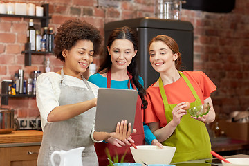 Image showing happy women with tablet pc cooking in kitchen