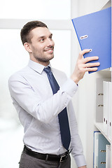 Image showing handsome businessman picking folder at office