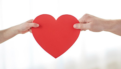 Image showing close up of child and male hands holding red heart