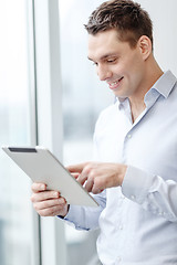 Image showing smiling businessman with tablet pc in office