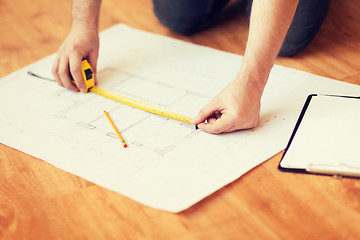 Image showing close up of male hands measuring blueprint