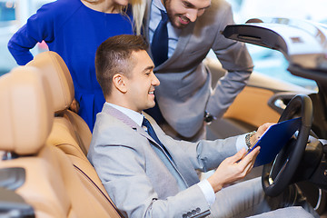 Image showing happy couple with car dealer in auto show or salon