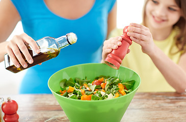 Image showing close up of happy family cooking salad in kitchen