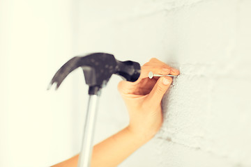 Image showing architect hammering nail in wall