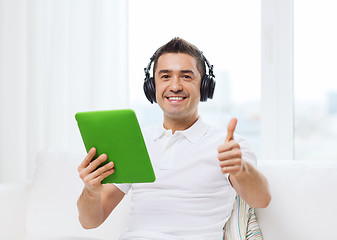 Image showing smiling man with tablet pc and headphones at home