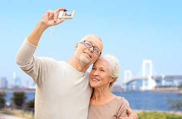 Image showing senior couple with camera over rainbow bridge