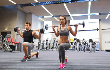 Image showing young man and woman training with barbell in gym