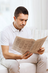 Image showing sad man reading newspaper at home