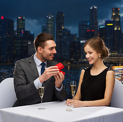 Image showing smiling couple with red gift box at restaurant