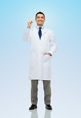 Image showing smiling doctor in white coat pointing finger up