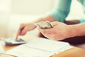 Image showing close up of man counting money and making notes