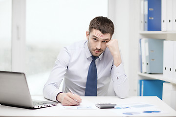 Image showing stressed businessman with laptop and documents