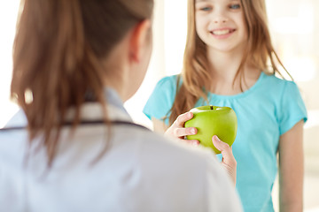 Image showing close up of doctor giving apple to happy girl