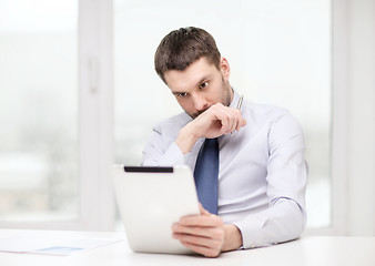 Image showing stressed businessman with tablet pc and documents