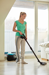Image showing happy woman with vacuum cleaner at home