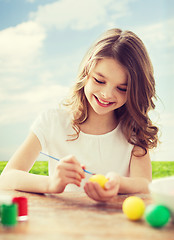 Image showing smiling little girl coloring eggs for easter