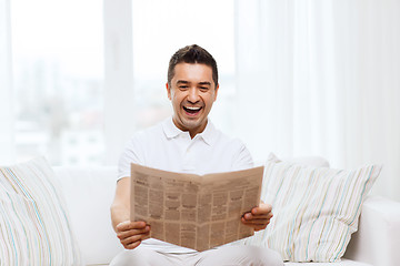 Image showing happy man reading newspaper and laughing at home