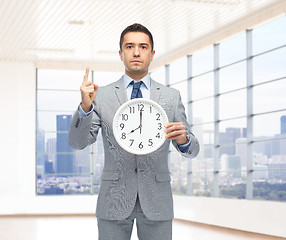 Image showing businessman in suit holding clock with 8 o'clock