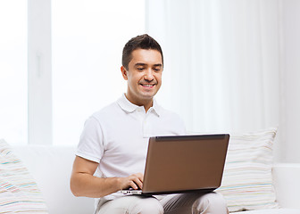 Image showing happy man working with laptop computer at home