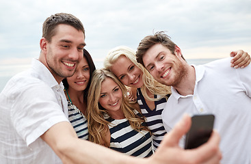 Image showing happy friends on beach and taking selfie