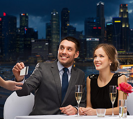 Image showing smiling couple paying for dinner with credit card
