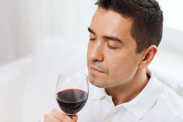 Image showing happy man drinking red wine from glass at home