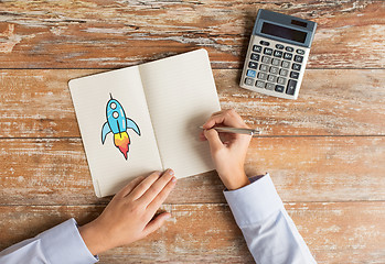 Image showing close up of hands with calculator and notebook