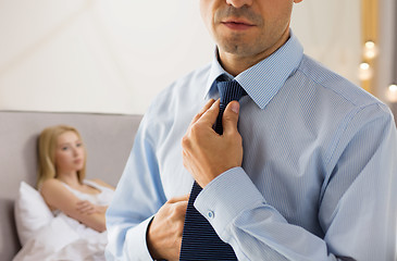 Image showing close up of man adjusting tie on neck in bedroom