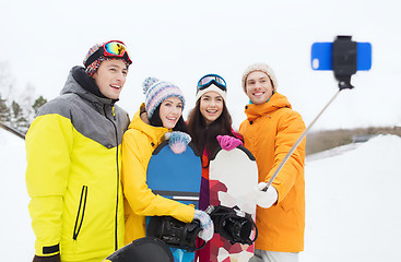 Image showing happy friends with snowboards and smartphone