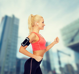 Image showing sporty woman running with smartphone and earphones