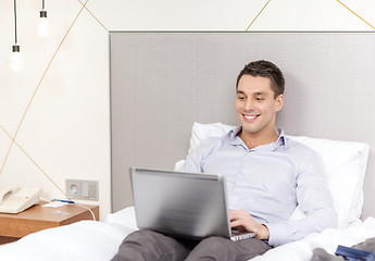 Image showing happy businesswoman with laptop in hotel room