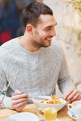 Image showing happy young man having dinner at restaurant