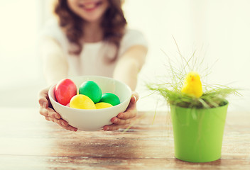 Image showing close up of girl holding bowl with colored eggs