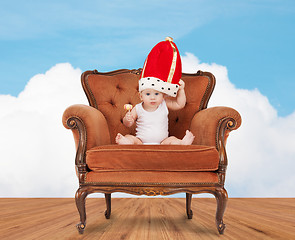 Image showing baby in royal hat with lollipop sitting on chair