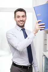 Image showing handsome businessman picking folder at office