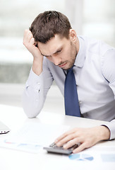 Image showing stressed businessman with laptop and documents